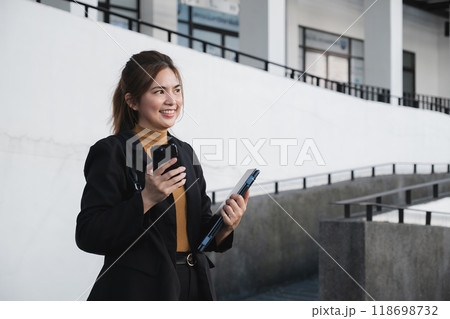 A woman in a business suit holding a cell phone and a briefcase 118698732