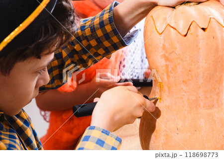 Close-up shot of a boy carving Halloween pumpkin with special saw knife 118698773