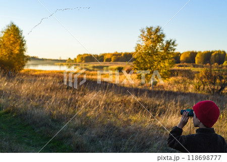 Young bird watcher looking at a flock of birds preparing to migrate to Southern countries on Autumn day Young bird watcher looking at a flock of birds preparing to migrate to Southern countries on Autumn day 118698777