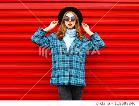Fashion pretty woman wearing a black hat coat jacket over colorful red background 118698840