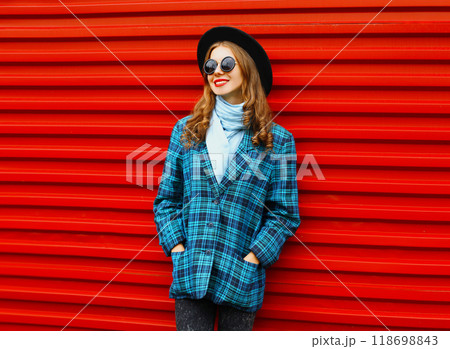 Fashion pretty woman wearing a black hat coat jacket over colorful red background Fashion pretty woman wearing a black hat coat jacket over colorful red background 118698843
