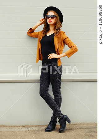 Fashion elegant woman model wearing a black hat sunglasses jacket posing over grey background 118698869