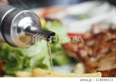 Healthy Salad Prep with Olive Oil in a Cozy Restaurant. Enjoy a fresh and wholesome meal 118699213