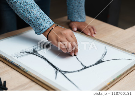Person sketching abstract lines on paper with charcoal in a creative studio Person sketching abstract lines on paper with charcoal in a creative studio 118700151