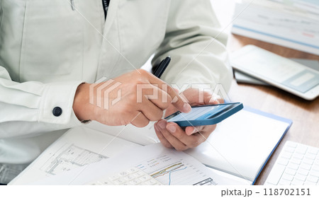 スマホを操作する作業服の男性の手元 118702151