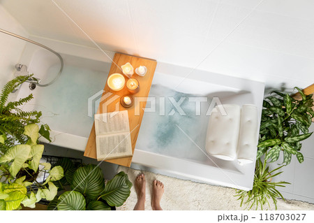A woman stands in front of a bathtub filled with white foam. The concept of relaxation, self-love 118703027