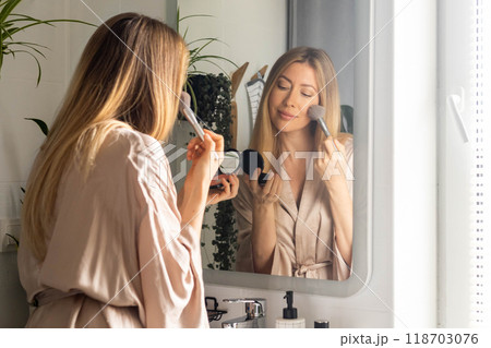 A young beautiful woman combs her long hair and takes care of her skin in the morning at home A young beautiful woman combs her long hair and takes care of her skin in the morning at home 118703076