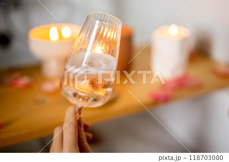 A young beautiful girl drinks wine while lying in a bath with foam and petals. Candles and plants. A young beautiful girl drinks wine while lying in a bath with foam and petals. Candles and plants. 118703080
