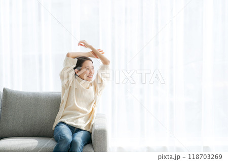 ソファに座って伸びをする女性 118703269