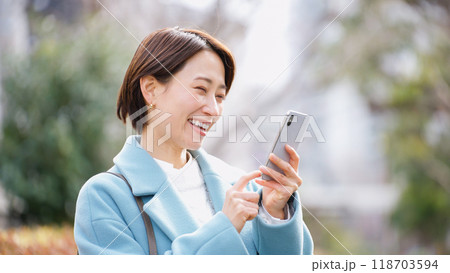 スマホを使う女性（冬服・上着・コート） 118703594