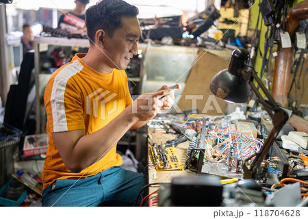 repair man takes a photo of a circuit using a cell phone 118704628