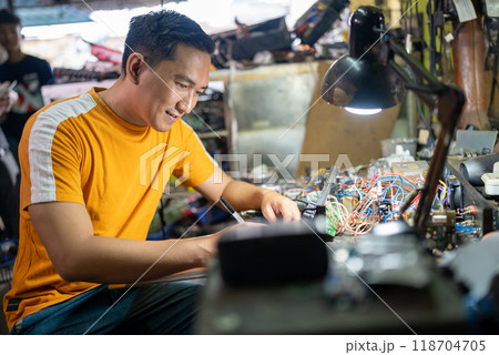 portrait of an electrical repairman sitting at a work table in a workshop 118704705