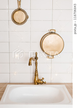 White sink with a gold faucet and a pot hanging above it 118706843