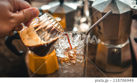 Making iced coffee. Pouring coffee into a glass with ice. 118706949