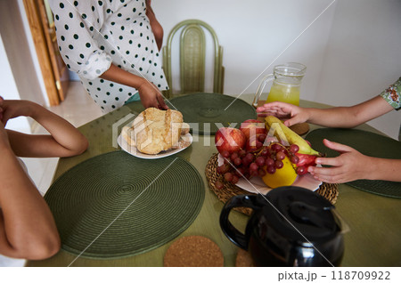 Family gathering around a table with fresh fruit, bread, and lemonade, creating a cozy and inviting atmosphere. 118709922