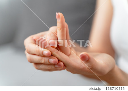 Closeup young woman sitting on sofa holds her wrist. hand injury, feeling pain. Health care. Closeup young woman sitting on sofa holds her wrist. hand injury, feeling pain. Health care. 118710313