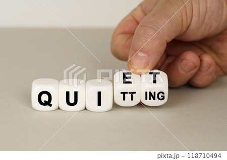 On a gray surface are white cubes with the inscription - QUIET or QUITTING 118710494
