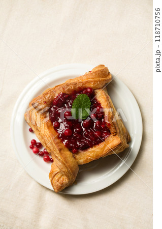 A delicious dessert, puff pastry cake with berry filling. Cranberry dessert on a light color 118710756