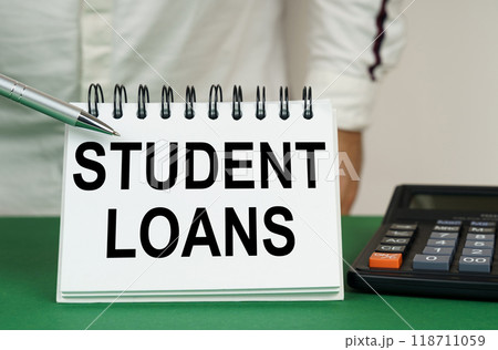On a green surface, a calculator and a notepad with the inscription - Student loans 118711059