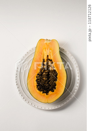 Half of a beautiful juicy ripe papaya on a white plate on a white table 118712126