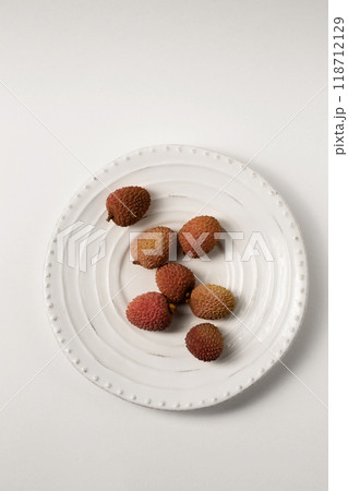 Ripe tropical lychee berries on a white plate on a white table Ripe tropical lychee berries on a white plate on a white table 118712129