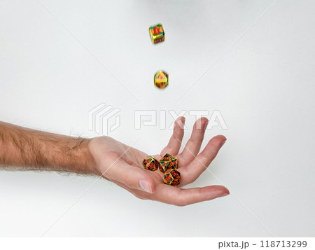 Tossed colorful dice in mid-air over hand against white background Tossed colorful dice in mid-air over hand against white background 118713299