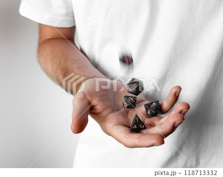 Close-up of person tossing polyhedral dice against a white background Close-up of person tossing polyhedral dice against a white background 118713332