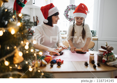 Mother and daughter baking Christmas cookies together at home Mother and daughter baking Christmas cookies together at home 118714145