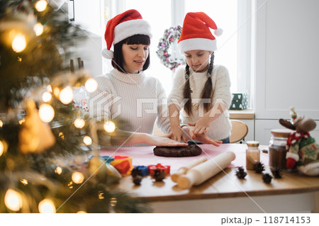 Mother and daughter baking with Christmas spirit in cozy kitchen Mother and daughter baking with Christmas spirit in cozy kitchen 118714153