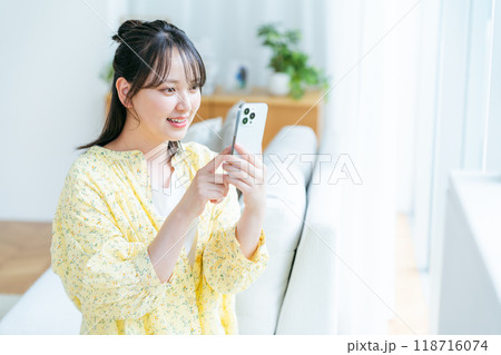 部屋でスマホを操作する若い女性 部屋でスマホを操作する若い女性 118716074