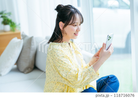 部屋でスマホを操作する若い女性 部屋でスマホを操作する若い女性 118716076