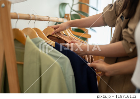 Females selecting clothes from a rack, enjoying their shopping experience together. 118716112