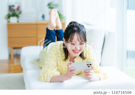 部屋でスマホを操作する若い女性 部屋でスマホを操作する若い女性 118716506