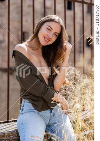 Woman in unbuttoned blouse posing near fence Woman in unbuttoned blouse posing near fence 118717567