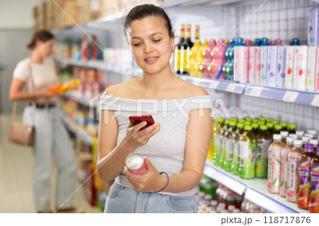 Girl reads QR code from aluminum can of drink in chinese supermarket Girl reads QR code from aluminum can of drink in chinese supermarket 118717876