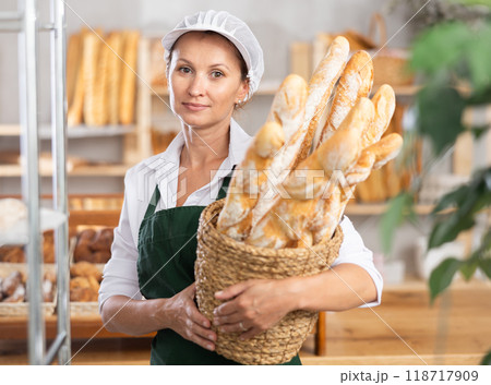 Female baker worker sells baguette, shows many products Female baker worker sells baguette, shows many products 118717909