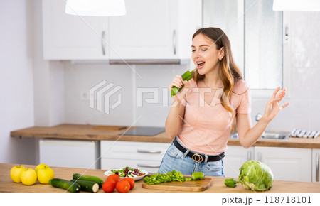 Happy housewife posing as singer at kitchen table Happy housewife posing as singer at kitchen table 118718101
