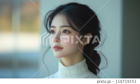 A young Korean woman gazing thoughtfully, showcasing her features in soft morning light indoors 118719151