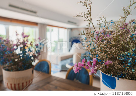 Bright and airy living space in a luxury hotel featuring large windows, vibrant floral arrangements, modern furniture, and a harmonious color scheme. 118719806