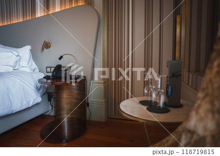 Experience luxury in this hotel room featuring a stylish bedside area, crisp white linens, and elegant striped wallpaper. Perfect for a sophisticated stay. 118719815