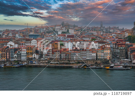 Vibrant view of Porto, Portugal, featuring the historic Ribeira district, Porto Cathedral, and traditional boats along the Douro River at dawn or dusk. 118719897