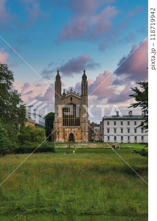 The iconic King's College Chapel in Cambridge, UK, with its Gothic architecture, lush green lawn, and a vibrant, partly cloudy sky in the background. 118719942