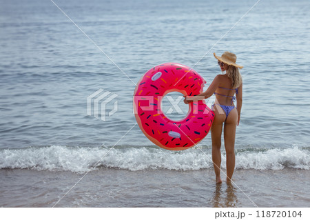 Athletic young woman with sexy athletic ass in bikini with inflatable swim ring. Outdoor lifestyle picture on a sunny summer day. 118720104