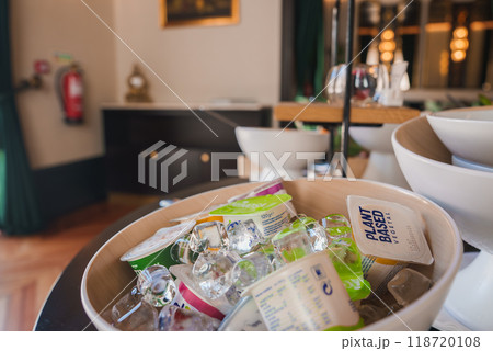 A sophisticated hotel interior featuring a wooden bowl with plant-based yogurt on ice, elegant decor with a black cabinet, gold accents, and a framed painting. A sophisticated hotel interior featuring a wooden bowl with plant-based yogurt on ice, elegant decor with a black cabinet, gold accents, and a framed painting. 118720108