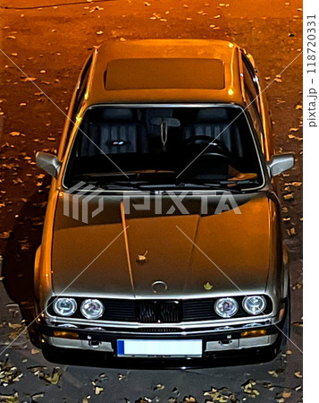 BMW E-30 in the parking lot is illuminated by street lights. Legendary car BMW E-30.Old BMW 3 series with angel eyes optics. BMW E-30 in the parking lot is illuminated by street lights. Legendary car BMW E-30.Old BMW 3 series with angel eyes optics. 118720331