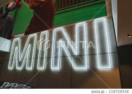 A striking white neon MINI sign on a concrete wall, partially covered by a vibrant mural of a person in red, located in a London commercial space. A striking white neon MINI sign on a concrete wall, partially covered by a vibrant mural of a person in red, located in a London commercial space. 118720338