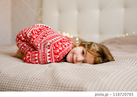 A girl in a Christmas pajama is lying on the bed and smiling 118720785