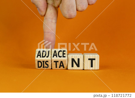 Adjacent or distant symbol. Businessman turns beautiful wooden cubes and changes word Distant to Adjacent. Beautiful orange table orange background. Copy space. Business adjacent or distant concept. Adjacent or distant symbol. Businessman turns beautiful wooden cubes and changes word Distant to Adjacent. Beautiful orange table orange background. Copy space. Business adjacent or distant concept. 118721772