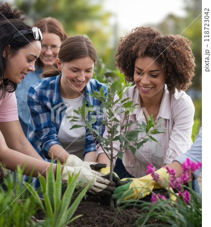 A woman smiles among the plants in a community garden. Surrounded by women working together, the vibrant scene symbolizes gender equality and environmental sustainability. A woman smiles among the plants in a community garden. Surrounded by women working together, the vibrant scene symbolizes gender equality and environmental sustainability. 118723042