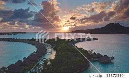 Luxury wooden villas hotel in coral reef lagoon. Exclusive resort overwater bungalows on Bora Bora. Remote romantic honeymoon, exotic summer travel. Aerial drone flight. Amazing colorful sunset sky Luxury wooden villas hotel in coral reef lagoon. Exclusive resort overwater bungalows on Bora Bora. Remote romantic honeymoon, exotic summer travel. Aerial drone flight. Amazing colorful sunset sky 118723104